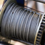 A close-up shot of a metal winch coil with steel cable wire on it